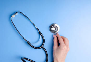 Medical Concept. Top view of stethoscope in hand on blue background. Flat lay and copy space