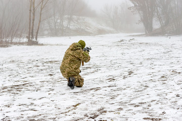 A military soldier in camouflage with a weapon goes on the offensive in winter.