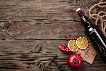 Ripe pomegranate fruit with a glass of wine, a bottle and a corkscrew on a wooden background