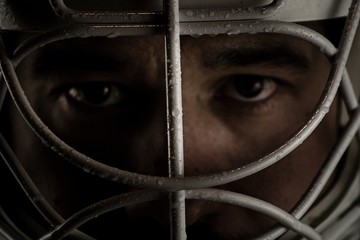 Detail of a male face in a goalie hockey mask.This is a detail hockey goalie. He is concentrated on game.