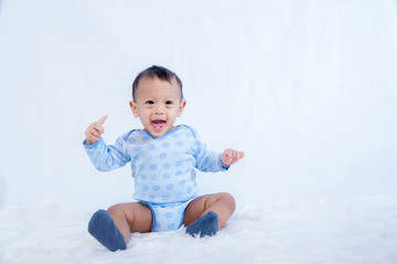 Fototapeta premium smile baby boy is shooting in the studio. fashion image of baby and family. Lovely baby sit down on a soft white carpet. image for background, wallpaper, copy space, objects, fashion and article