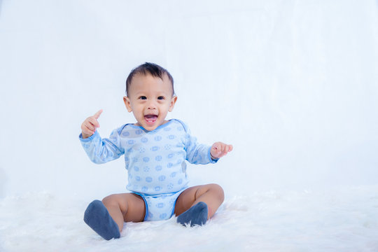 smile baby boy is shooting in the studio. fashion image of baby and family. Lovely baby sit down on a soft white carpet. image for background, wallpaper, copy space, objects, fashion and article