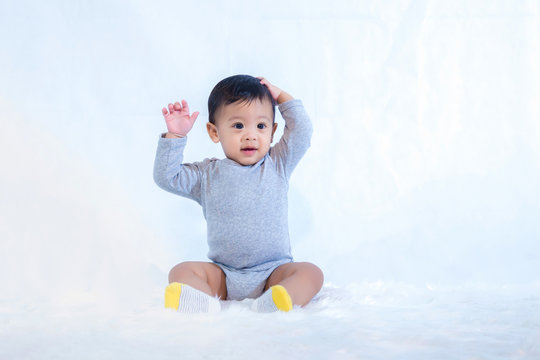 smile baby boy is shooting in the studio. fashion image of baby and family. Lovely baby sit down on a soft white carpet. image for background, wallpaper, copy space, objects, fashion and article