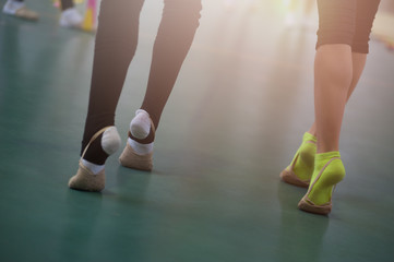 Close up of feet of young gymnasts in black leggins and white and green socks on the floor in the dance studio. Close up of feet of young sportsmen at the gym club