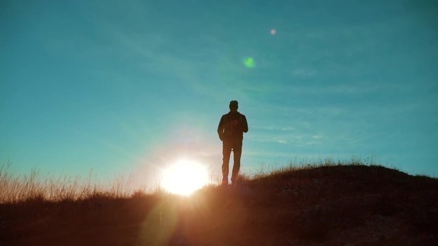Male man worth it tourist with backpack on the top of the mountain. smartphone navigation. sunlight stands on top of a mountain. slow motion video. man silhouette at sunset . hikers adventure and the