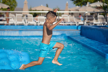 Naklejka premium Boy having fun in swimming pool at hotel. He making jump from inflatable mattress into water.