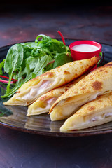 Thin pancakes stuffed with ham and melted cheese served with with spinach, arugula, corn and chard salad
