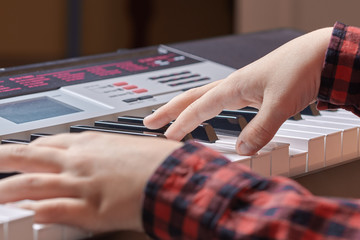 Kid’s hands on the electric synthesizer playing a melody.