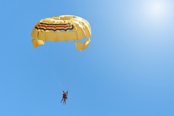 People have fun in summer. Flying on a parachute in sky.