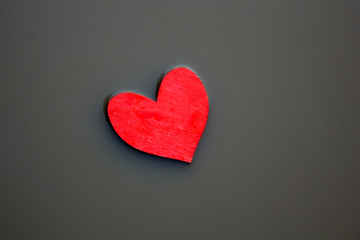 Red wooden heart in a grey muddy slough background