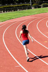 Young Woman Running On Track From Back