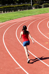 Fototapeta premium Young Woman Running On Track From Back