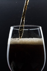 A glass of cola beverage with a salt. On a black background.