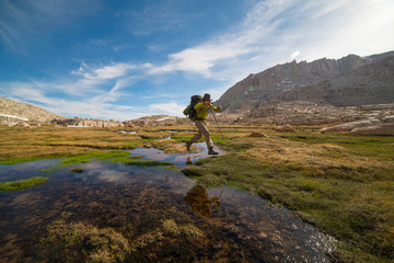 Hiker jumps stream in sierra nevada