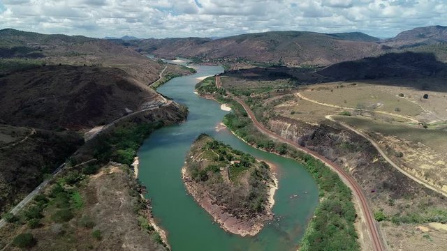 Drone landscape image along the course of the River Doce. Small island, plantations and houses below. In the background mountains and cloudy sky. Atlantic Forest Biome.