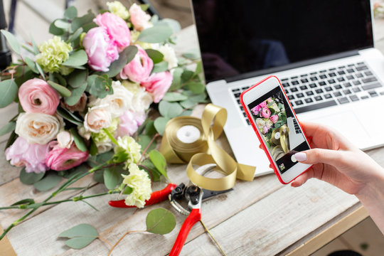 Young friendly female florist makes a photo of bouquet. Woman blogger and content creators of social networks and blog flower shop. The concept of online store and floral delivery. SMM promotion.