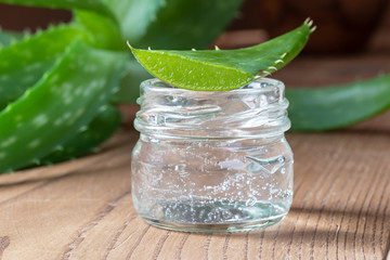 Aloe vera gel in a glass jar with fresh aloe vera leaf