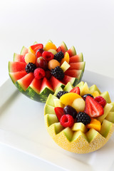 Fancy cut melon and watermelon with assorted fruit inside on a white background