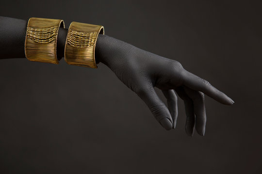 Black woman's hand with gold jewelry. Oriental Bracelets on a hand. Gold Jewelry and luxury