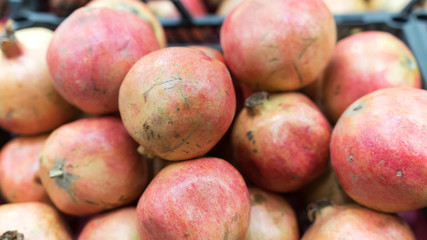 Closeup of red grapefruits in the market. Top view of ripe red organic pomegranates in market. Fresh pomegranates blurred image