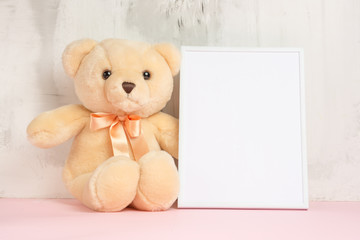 Children's toys, a teddy bear and a frame on a light wall background, for design, layout. Baby shower