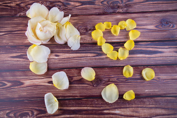 Saint Valentines day composition. Heart made of yellow rose petals laying on wooden table