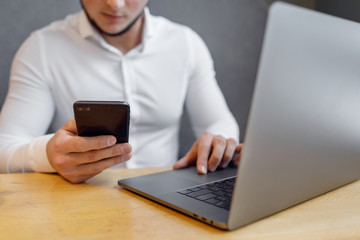 Portrait of Young man with a mobile phone sitting at cafe using laptop.