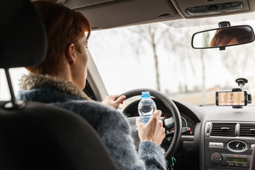 woman drinks water while driving a car