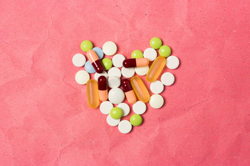 Figure in the shape of a heart lined pills and capsules. Top view.