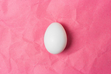White egg isolated on pink crafted background without text