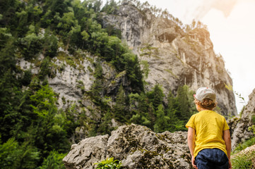 Naklejka na ściany i meble A 6-years blond boy near a rocky mountain