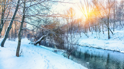 Obraz premium Winter landscape by a river in the sunset