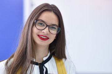Beautiful female student wearing glasses standing at university campus interior.