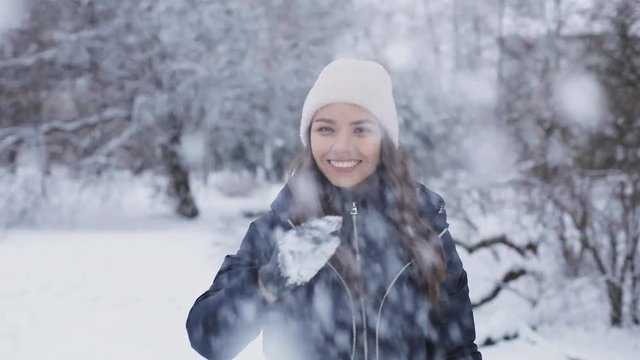 Atractive beautiful brunette woman еркщці snow balls in the winter park