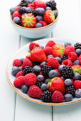 Fresh berry salad on blue dishes. Vintage wooden background.