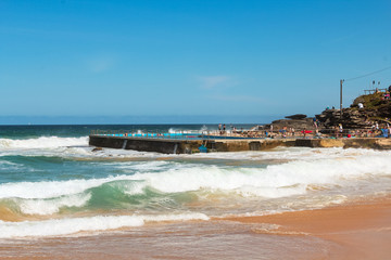 Famous rock pool in Sydney at Curl Curl Beach, one of the Northern beaches of Sydney, on a sunny summer day with waves to surf (Sydney, Australia)
