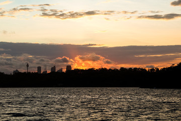 Fototapeta premium Dramatic sunset behind the skyline of Sydney as seen from Manly ferry on a warm summer evening (Sydney, New South Wales, Australia)