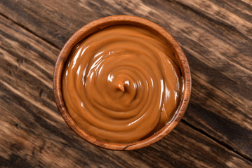 Dulce de leche bowl isolated on wooden background