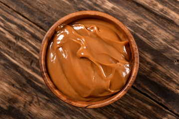 Dulce de leche bowl isolated on wooden background