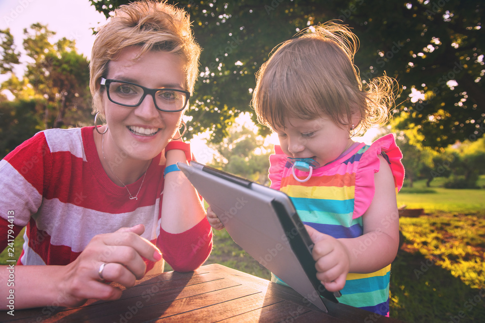 Sticker mom and her little daughter using tablet computer