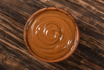 Dulce de leche bowl isolated on wooden background