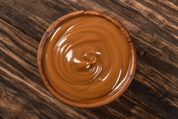 Dulce de leche bowl isolated on wooden background