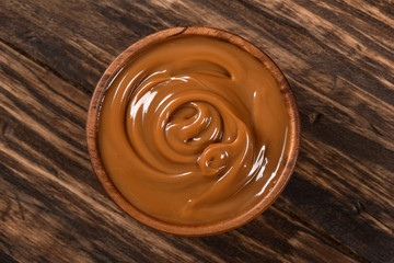 Dulce de leche bowl isolated on wooden background