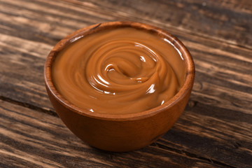 Dulce de leche bowl isolated on wooden background