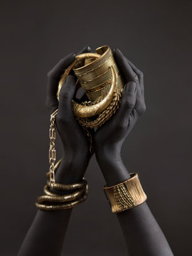 Black woman's hands with gold jewelry. Oriental Bracelets on a black painted hand. Gold Jewelry