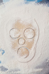 raw dough in shape of face rolled out on a flour covered table