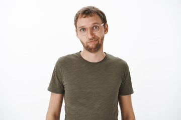 Fototapeta premium Portrait of cute and helpful good-looking male friend in glasses and green casual t-shirt smiling friendly at camera standing relaxed and calm over white background having normal conversation