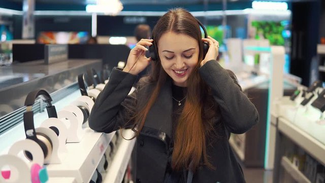 4k shot of a young beautiful woman testing headphones in modern store