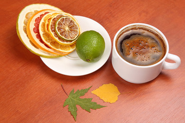 Black coffee in a white Cup surrounded by citrus dried fruits