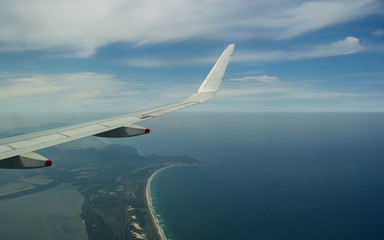 Fototapeta premium Wing of an airplane flying above the beach